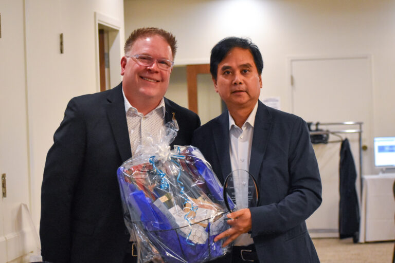 James Musgrave, Executive Director, posing with Sherman Chan at the BDFP 2026 Annual General Meeting. Sherman is holding a gift basket.